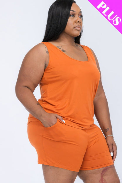 A woman wearing a solid burnt orange tank top and matching shorts with pockets against a plain white background.