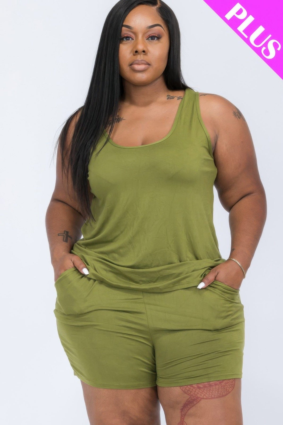 A plus-size model poses in an olive green sleeveless tank top and matching shorts set with side pockets against a plain white background.