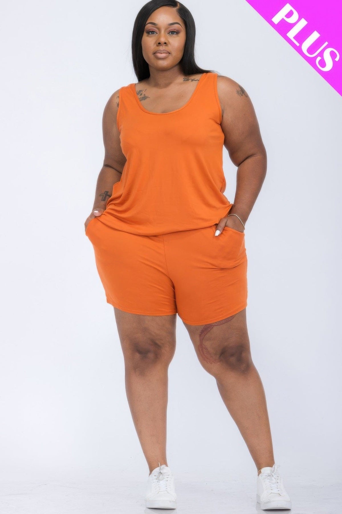 A plus size model wears a casual orange sleeveless tank top and matching shorts set, paired with white sneakers against a plain white background.
