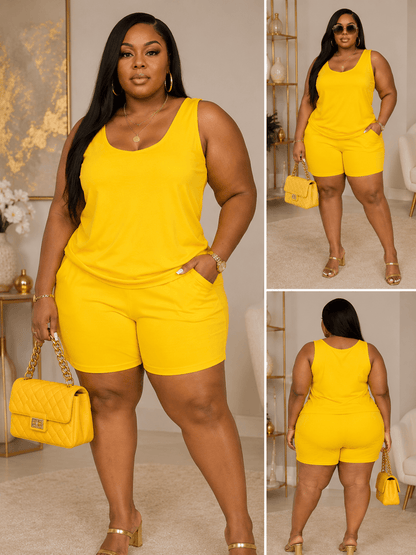 A woman models a vibrant yellow two-piece set consisting of a sleeveless tank top and matching shorts, styled with a quilted yellow handbag and gold heels in a well-lit indoor room.