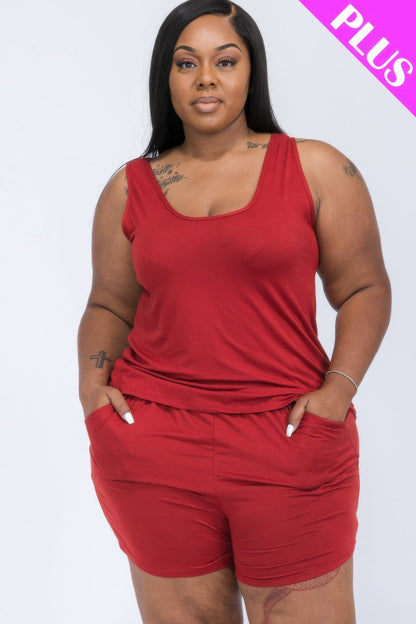 A woman wearing a solid red sleeveless scoop neck tank top paired with matching pull-on shorts that feature two side pockets.