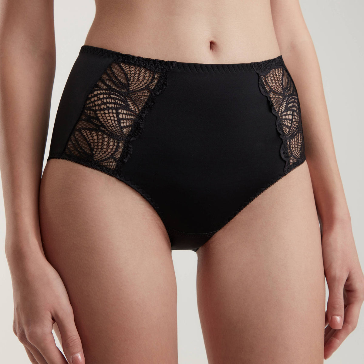 Black high-waisted briefs featuring decorative lace side panels on a model.