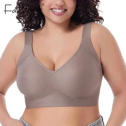 A person wears a taupe-colored, full-coverage wireless bra with wide shoulder straps and a smooth, minimalist design.