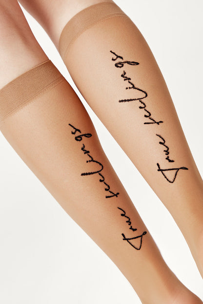 A pair of sheer, tan knee-high stockings featuring the phrase "true feelings" embroidered in black script along the outer side of each calf.