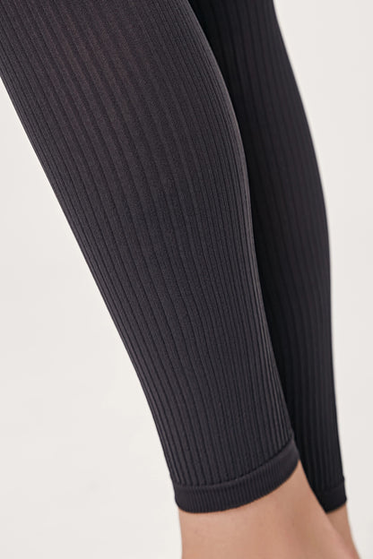 Close-up of a pair of charcoal grey ribbed leggings worn on the lower legs.