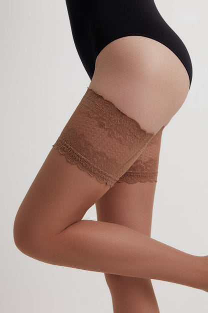 A pair of brown lace-top stay-up stockings on a person wearing a black bodysuit against a plain white background.