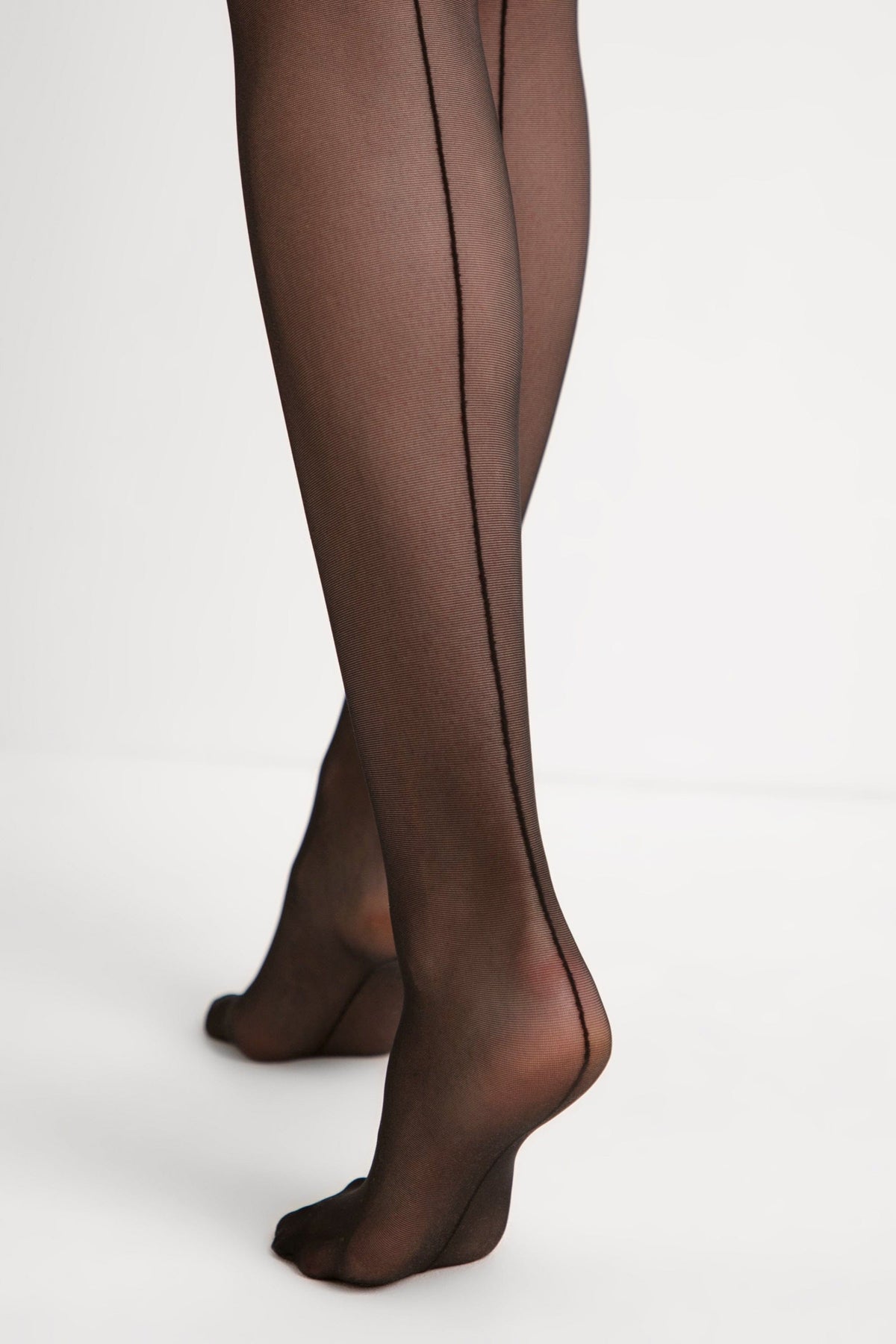 Sheer black tights with a prominent vertical seam running down the back of the legs.