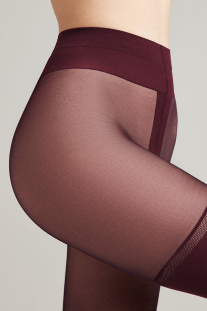 A close-up of burgundy sheer tights on a person's hip and upper thigh, featuring a high-waisted band and a reinforced panel detail.