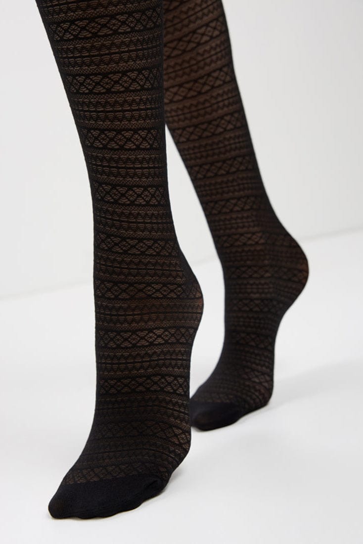 A pair of black opaque patterned tights featuring a repeating geometric diamond knit texture, displayed on a pair of legs against a plain white background.
