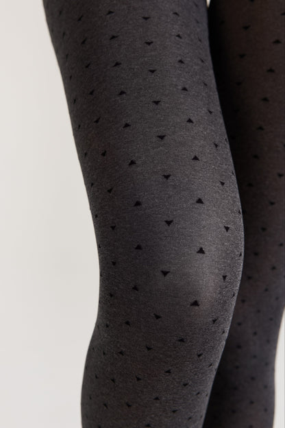 A close-up of dark grey patterned tights featuring a repeating print of small black triangles worn on a pair of legs.