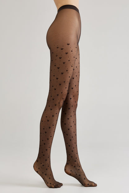 Black sheer pantyhose featuring an all-over pattern of small, scattered hearts on a light gray studio background.