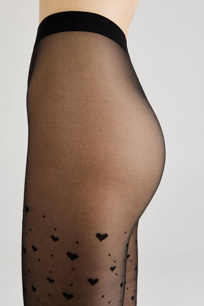 Sheer black tights featuring a pattern of small black hearts against a plain light gray background.