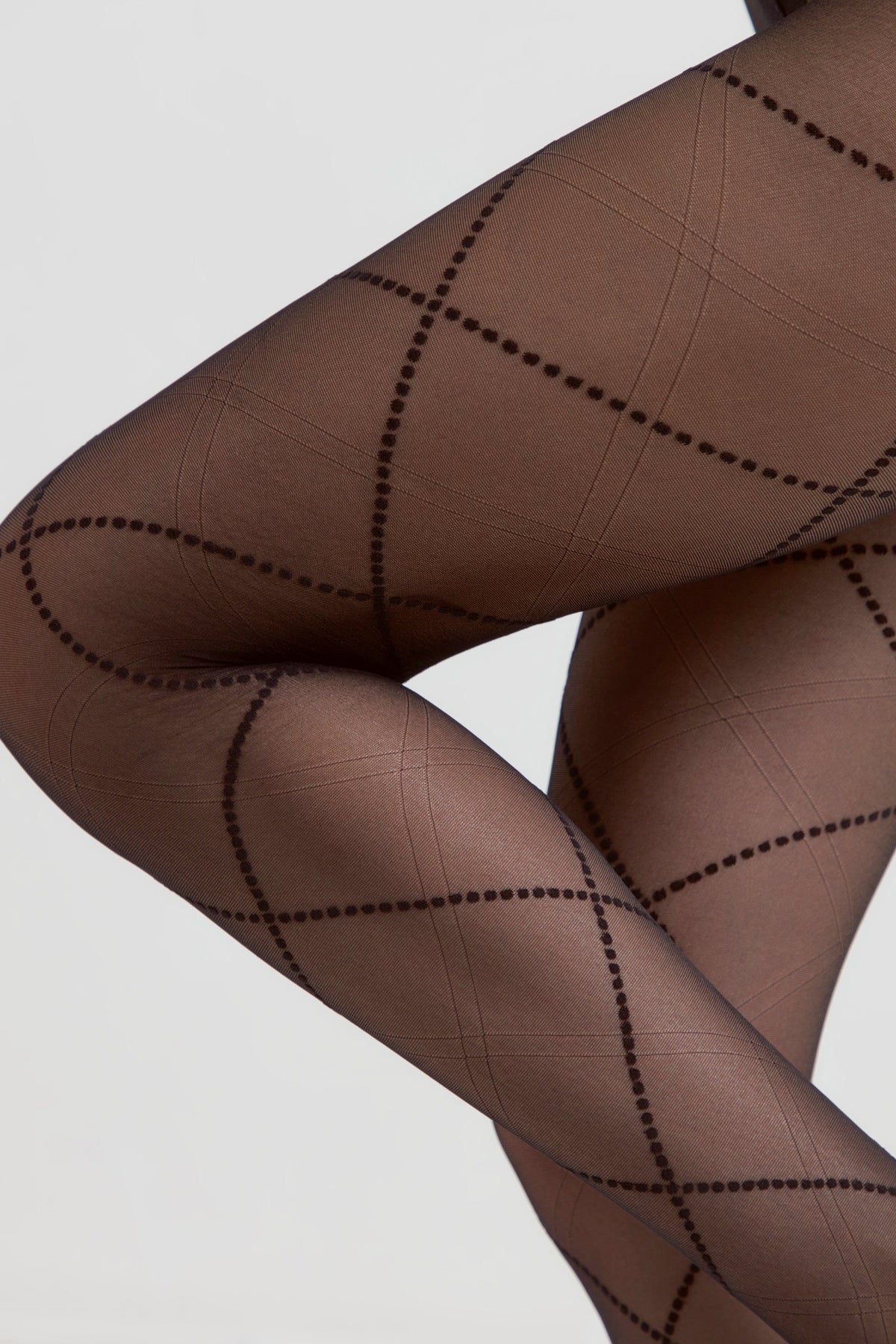 Sheer brown pantyhose featuring a dark repeating pattern of overlapping diamonds formed by dotted lines and fine intersecting diagonal grids.