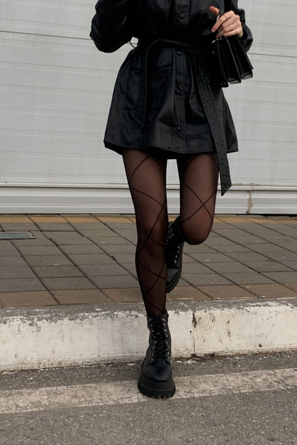 Black sheer tights featuring a diamond-shaped lattice pattern worn with a black belted mini dress and chunky black lace-up platform boots.