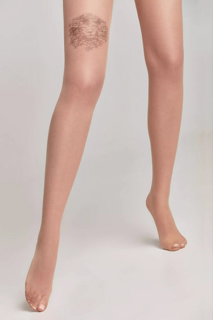 Sheer nude-colored tights worn on legs, featuring a decorative floral lion design on the upper right thigh against a plain light gray background.