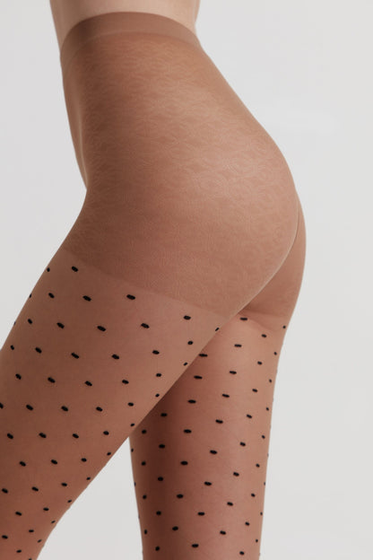 Sheer tan tights featuring a repeating pattern of small black dots on the legs and a solid reinforced panel at the upper thighs against a plain background.
