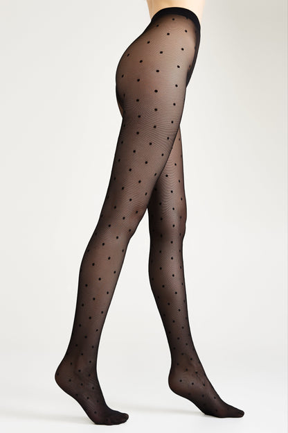 Sheer black tights patterned with small dark polka dots worn on a model against a plain light gray background.