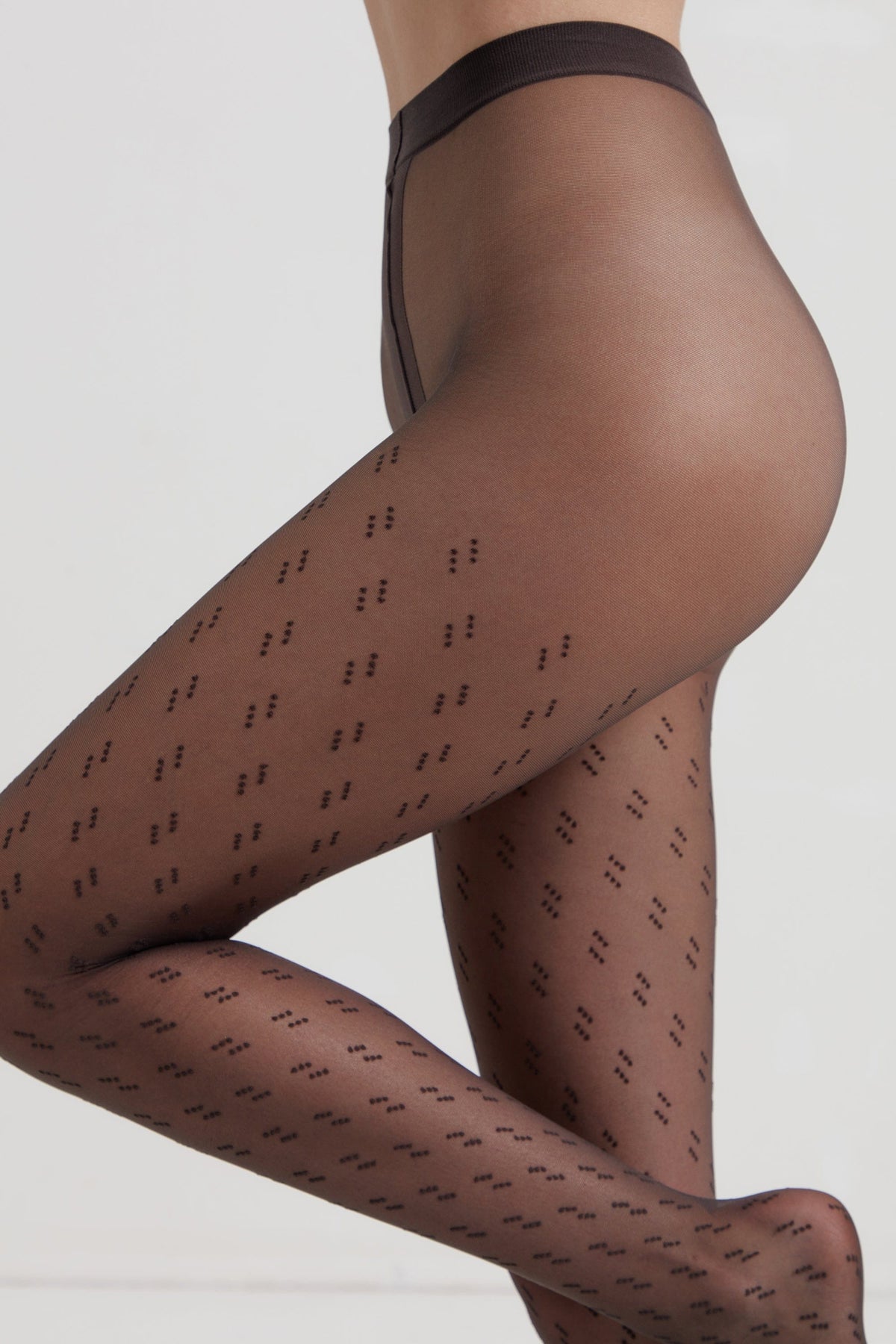Sheer black pantyhose with a pattern of small, repeating dark dots worn on a model's legs against a plain light background.