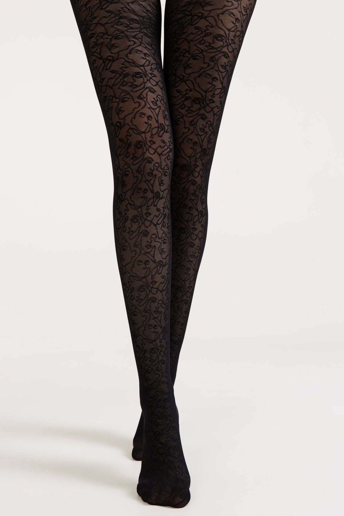 Black tights featuring a repeating continuous-line face pattern against a solid background worn on a pair of legs.