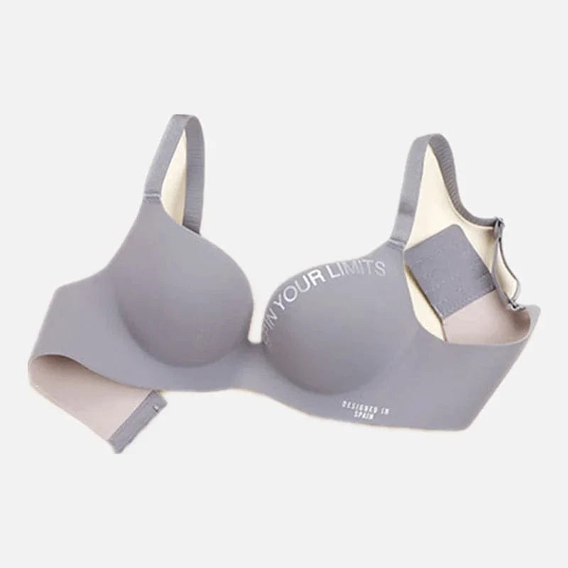 A gray seamless wireless bra with a molded cup design, featuring the white text "SPIN YOUR LIMITS" on the right cup and "DESIGNED IN SPAIN" on the side band.