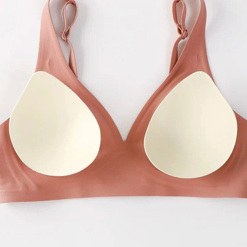 A mauve-colored wireless bralette with adjustable straps and removable cream-colored foam padding inserts laid flat against a white background.
