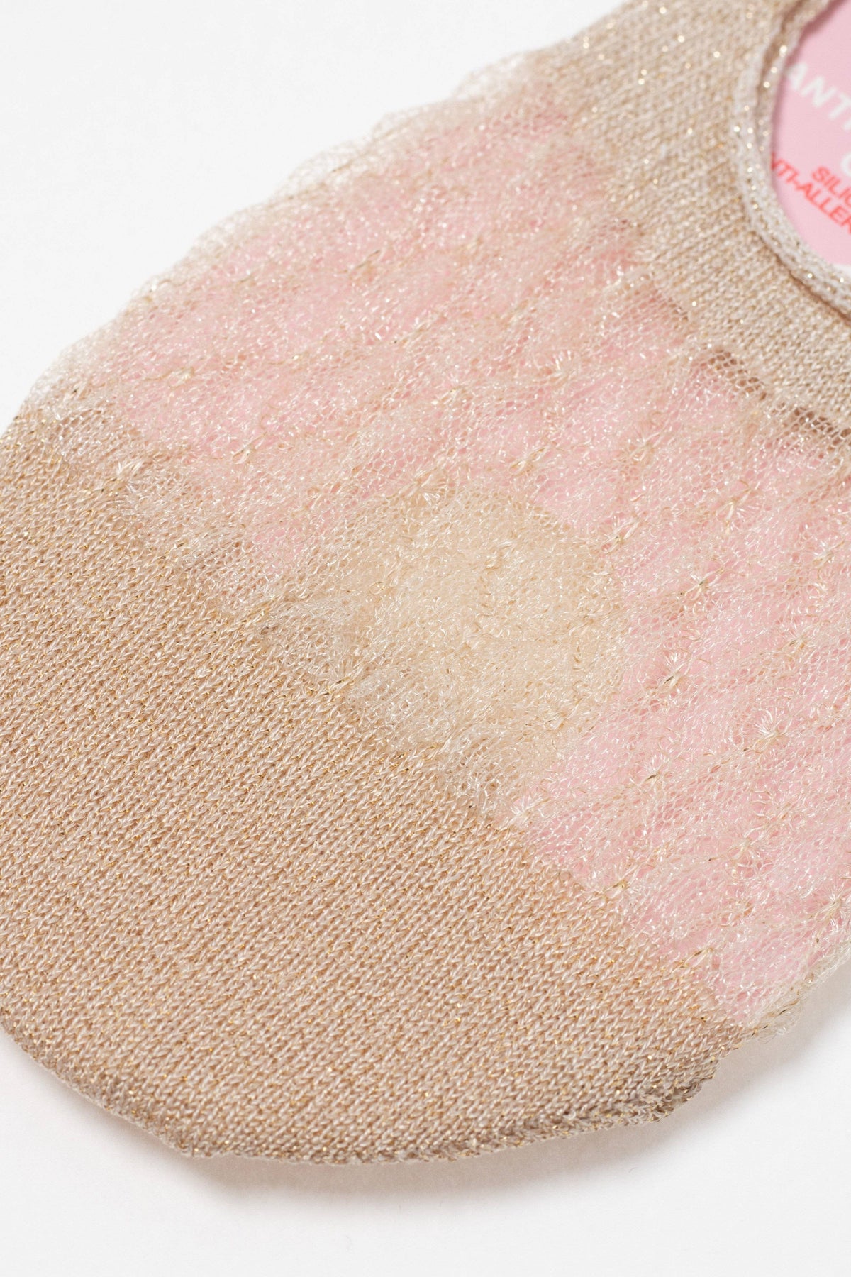 A close-up of a shimmering gold and pale pink no-show sock featuring a sheer, floral lace pattern over the mid-section and a solid metallic knit at the toe.