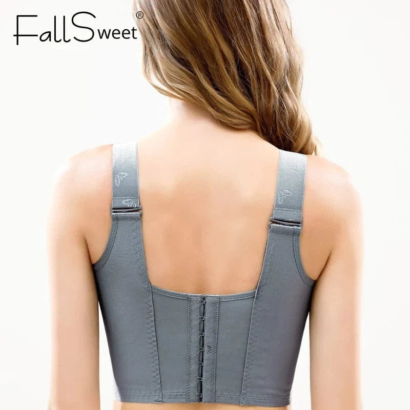 A woman seen from the back wearing a gray, wide-strap bra with a front-fastening hook-and-eye closure panel on the back.