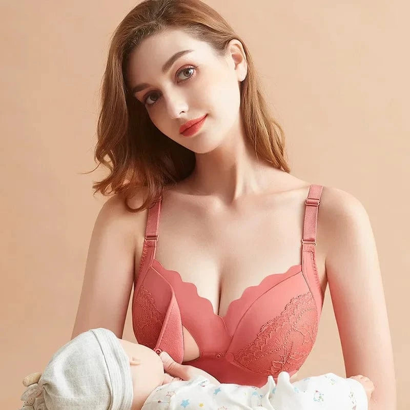 A dusty rose-colored nursing bra featuring scalloped edges, lace side panels, and a drop-down front clasp, worn by a woman breastfeeding her infant against a solid beige background.