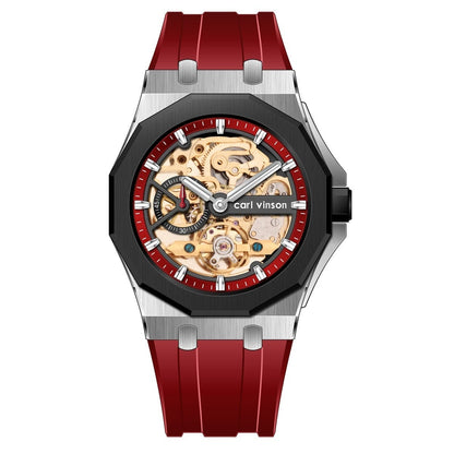 A skeleton watch featuring a silver-toned metal case, a black octagonal bezel, a red inner ring with white markers, and a red rubber strap.
