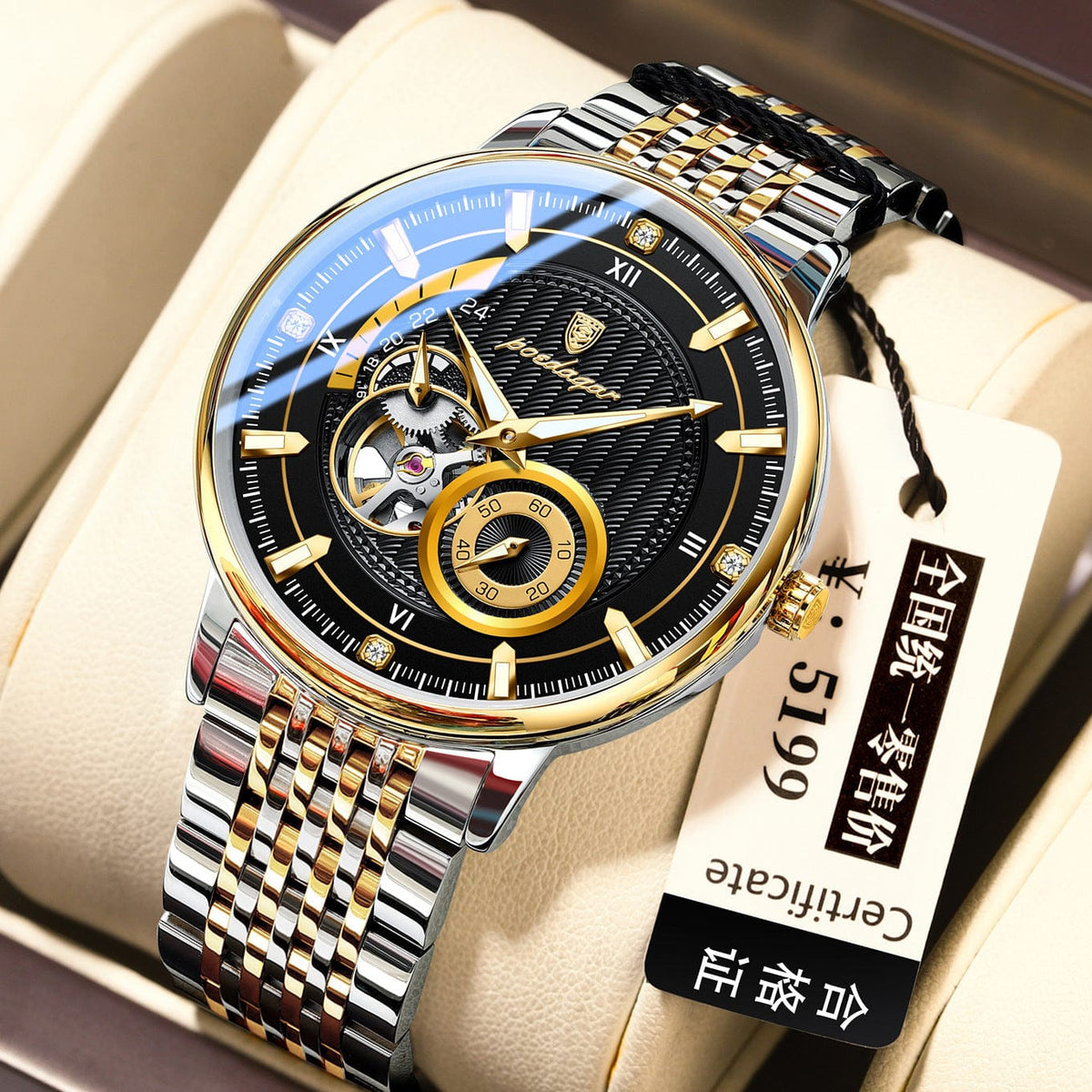 A round men's wristwatch with a black face, gold-tone accents, and a silver and gold metal link bracelet, presented inside a beige display box with an attached white tag.