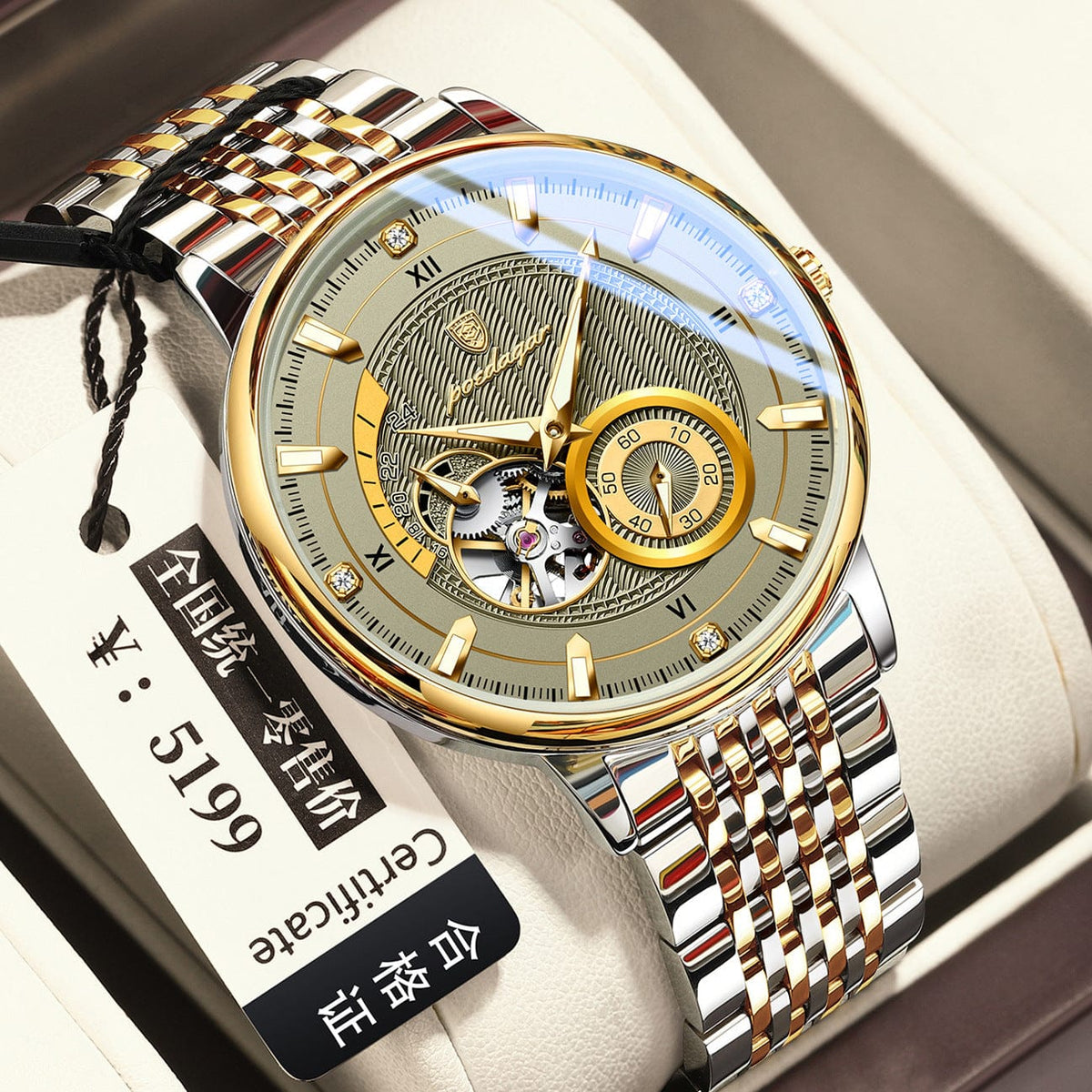 A silver and gold-tone stainless steel mechanical watch with a circular patterned green dial, exposed gear movement, and a tag indicating a price of 5199 yen rests on a white cushion.