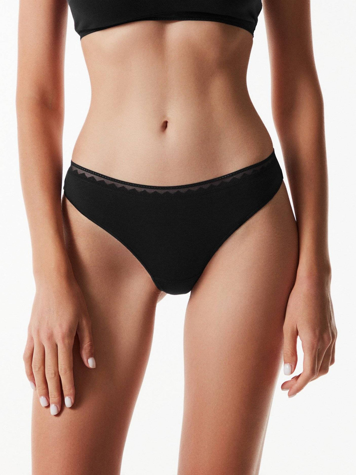 A pair of black bikini-style panties with a delicate geometric pattern along the elastic waistband on a person with a toned midsection.