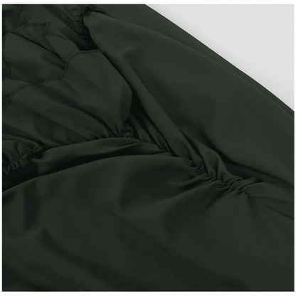 A close-up view of dark green fabric featuring gathered ruching detail along the side seam.