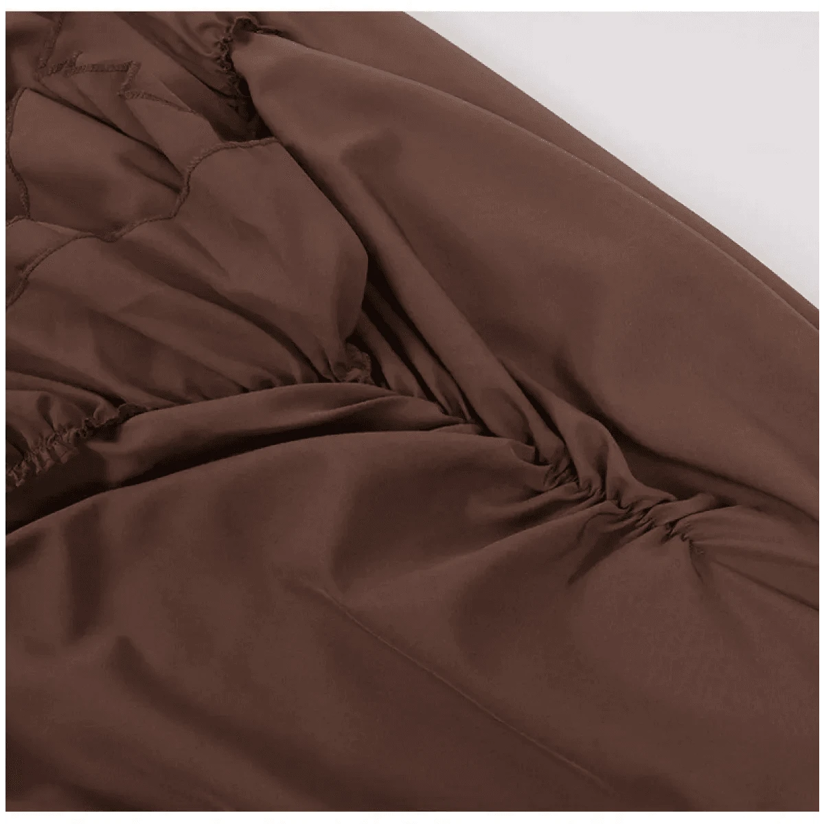 A close-up view of brown fabric featuring decorative zigzag stitching and gathered ruching detail along the side.