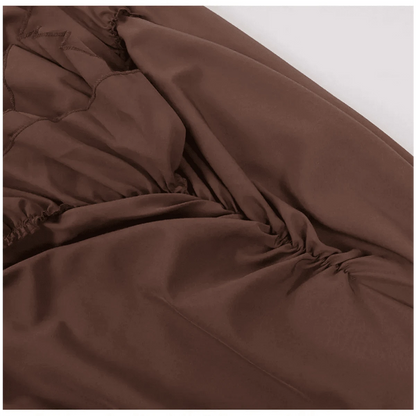 A close-up view of brown fabric featuring decorative zigzag stitching and gathered ruching detail along the side.