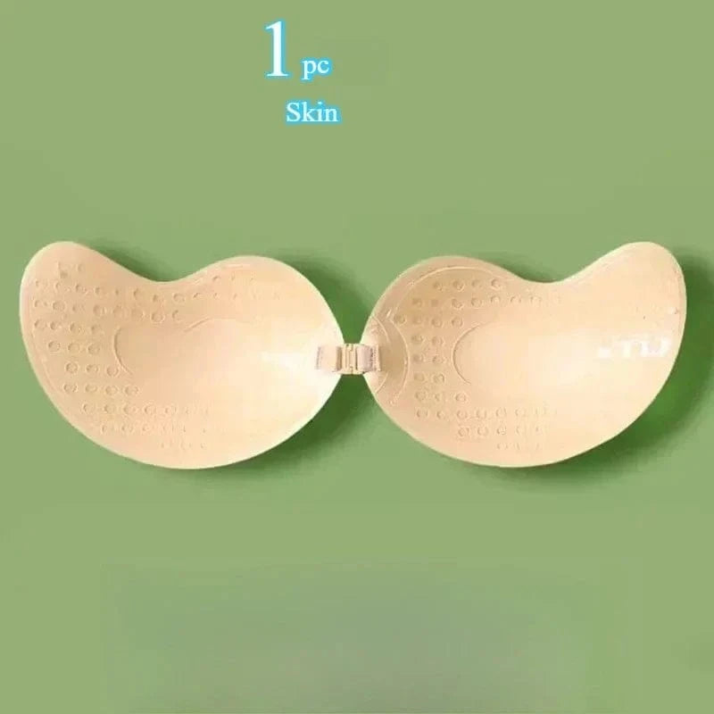 A beige adhesive strapless bra featuring a front clasp closure centered on a solid green background.