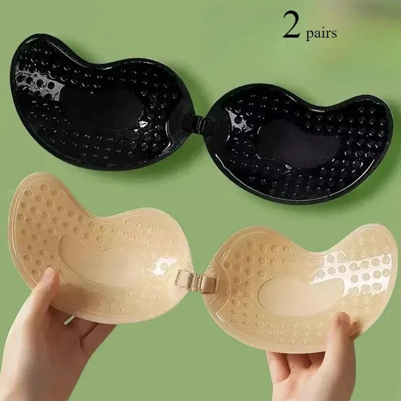 Two pairs of strapless adhesive silicone bras are displayed, one in black and one in beige, against a solid green background.