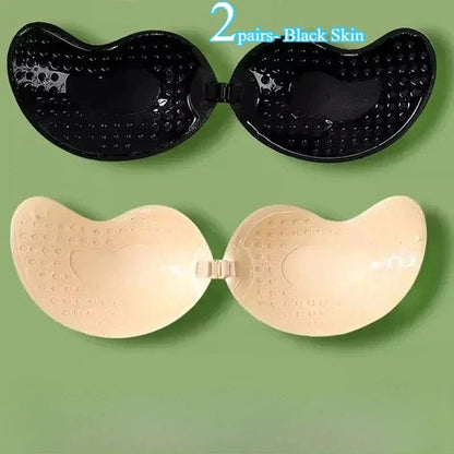 Two pairs of strapless adhesive bras, one in black and one in beige, are displayed against a solid green background.