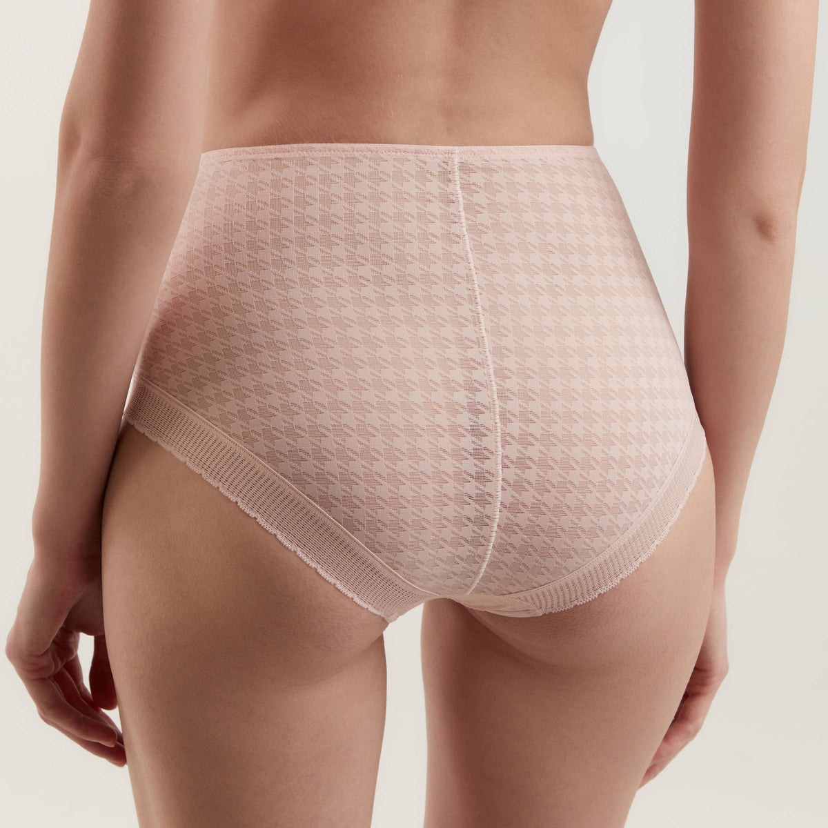 High-waisted pale pink underwear featuring a repeating houndstooth pattern and a textured lace trim along the leg openings, shown from the back on a model.