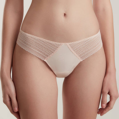 A pair of pale pink lace-trimmed bikini panties with a solid center panel worn on a model against a light background.