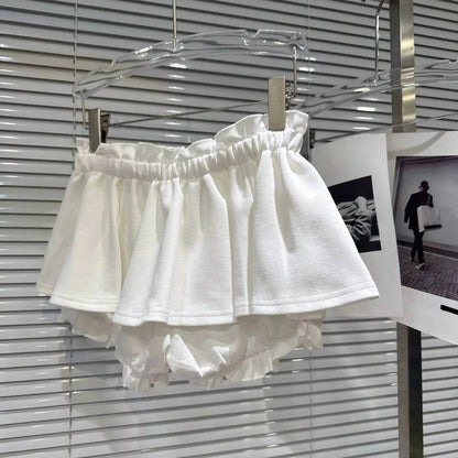 A pair of white frilled bloomers hanging from a clear hanger against a white slatted background.