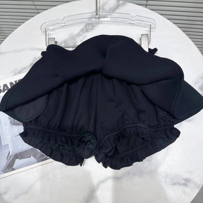 A black skort with an A-line skirt overlay and ruffled leg openings sits on a white marble table.