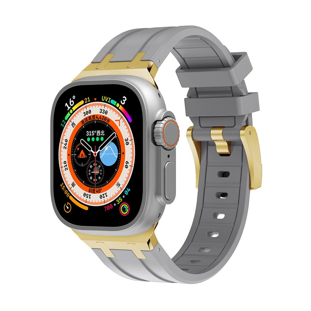A smartwatch with a rectangular display and a colorful circular face sits attached to a gray silicone watch band featuring gold-tone metal connectors and a matching buckle.