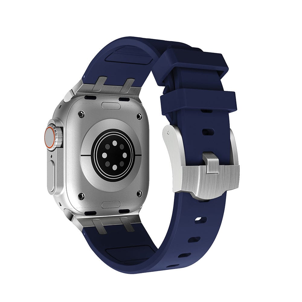 A smartwatch with a silver metallic rectangular case and a dark blue silicone band, shown from the back to reveal the circular heart rate sensor and metal buckle clasp.
