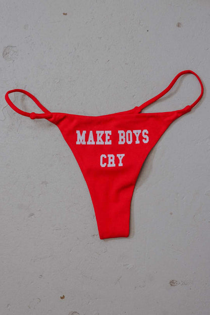 A red thong swimsuit bottom featuring the white text "MAKE BOYS CRY" printed on the front.