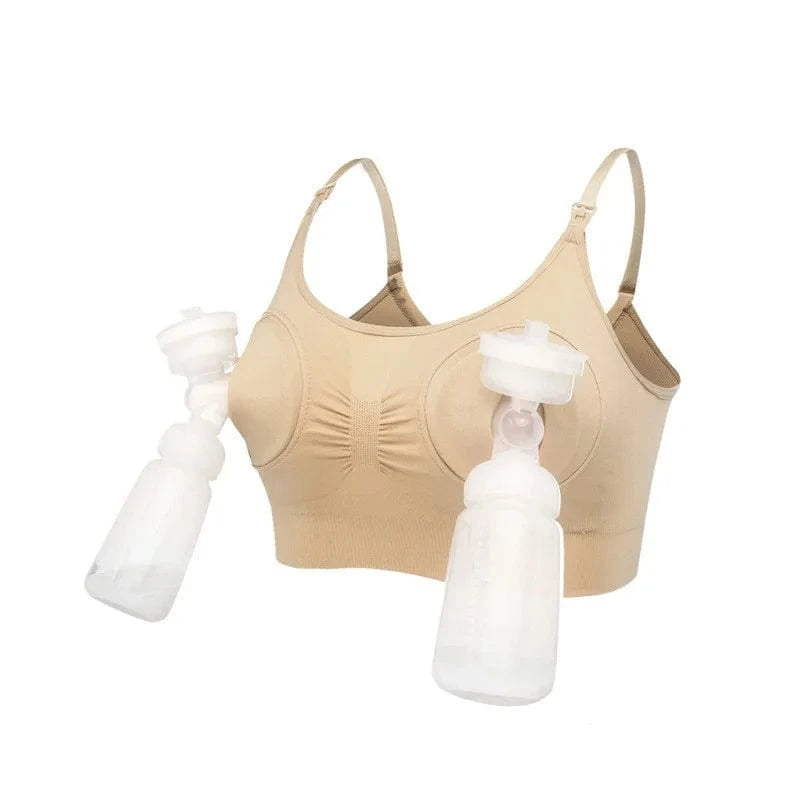 A beige hands-free pumping bra with two clear plastic breast pump collection kits attached to the front cups, set against a plain white background.