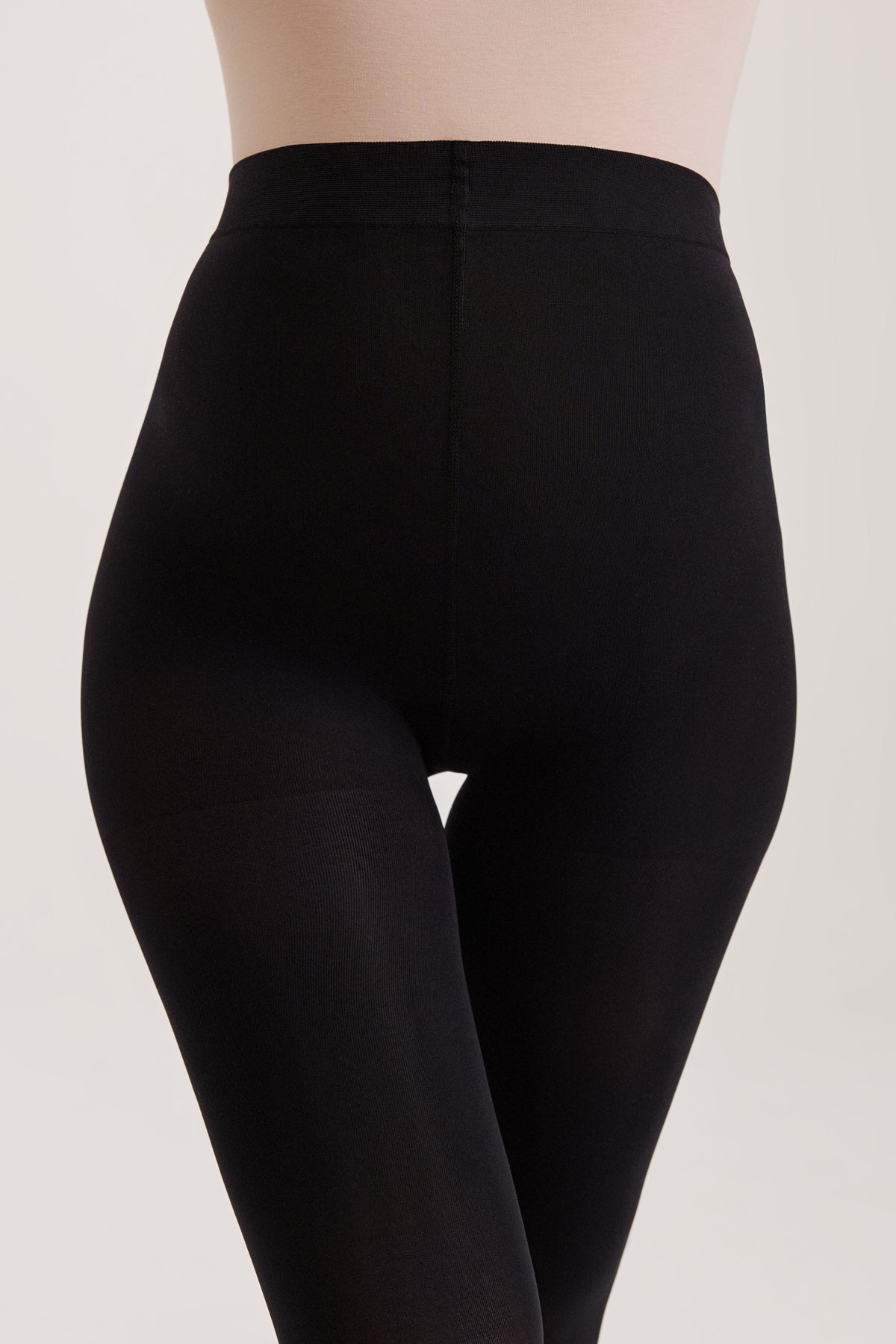 Opaque black tights worn on the lower body against a plain light background.