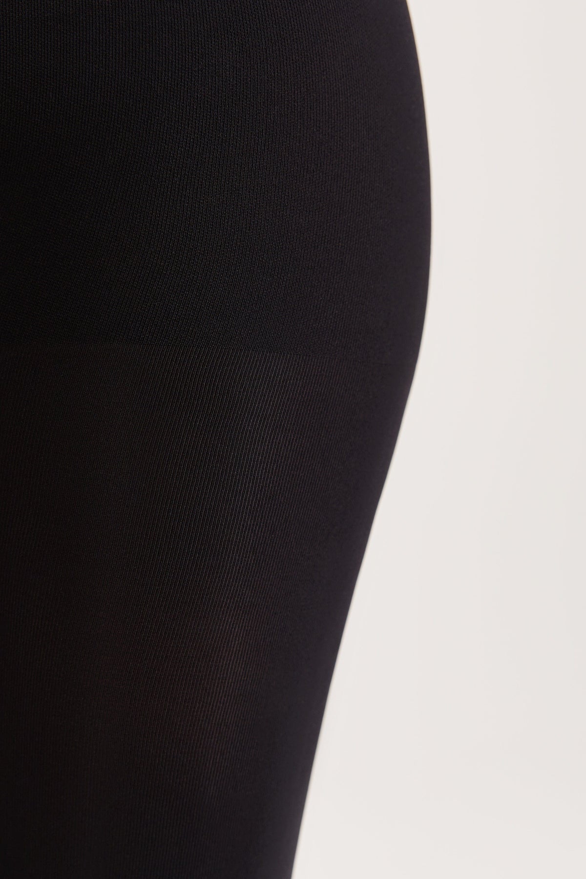 A close-up of solid black fabric, showcasing a smooth texture on the upper portion and a subtle vertical ribbing on the lower portion.