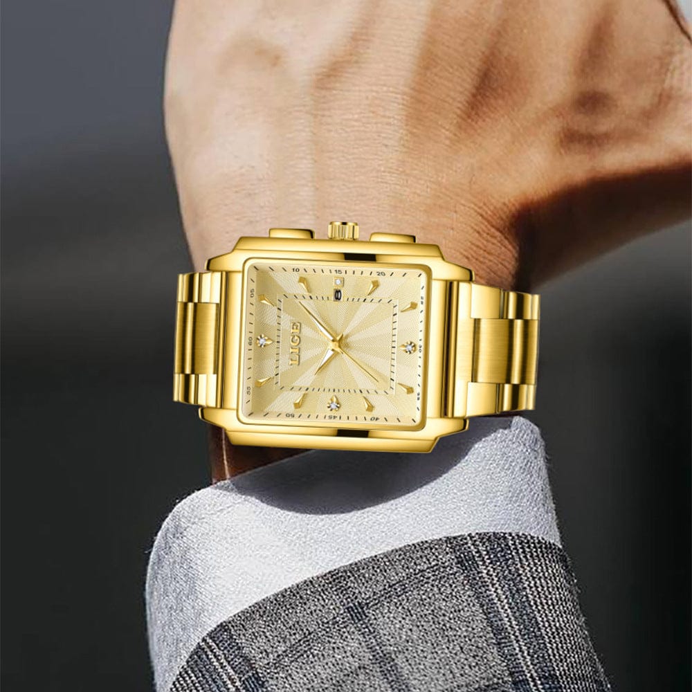 A gold-toned rectangular wrist watch with a sunray dial featuring small inlaid crystals at the quarter-hour marks and a matching gold link band, worn on a person's wrist against a gray pinstriped shirt sleeve.