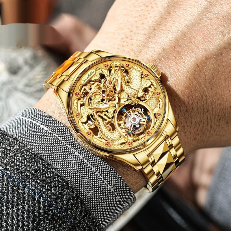A gold-toned skeletonized wristwatch features an intricate dragon motif on its dial and a metallic link strap worn on a person's wrist.